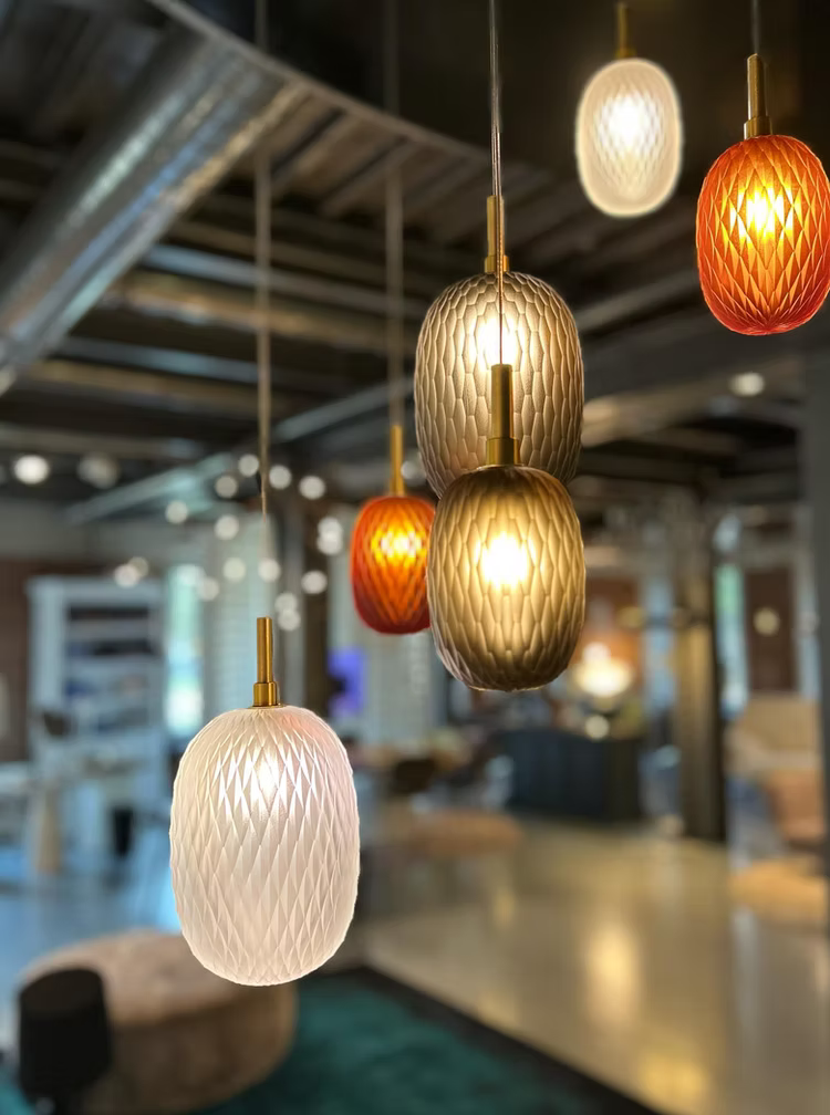 Modern pendant lights hanging in a blurred indoor setting, possibly a restaurant or cafe.