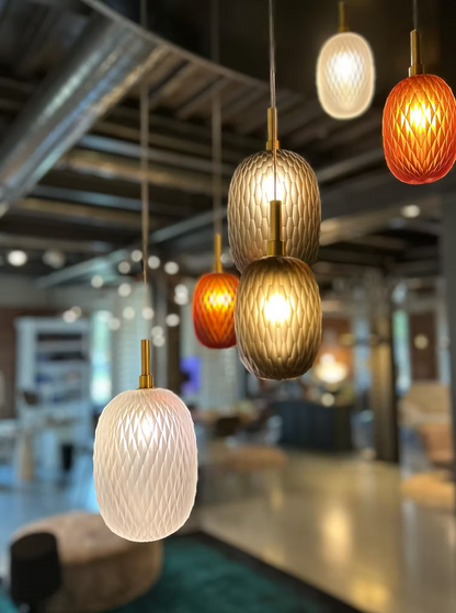 Modern pendant lights hanging in a blurred indoor setting, possibly a restaurant or cafe.