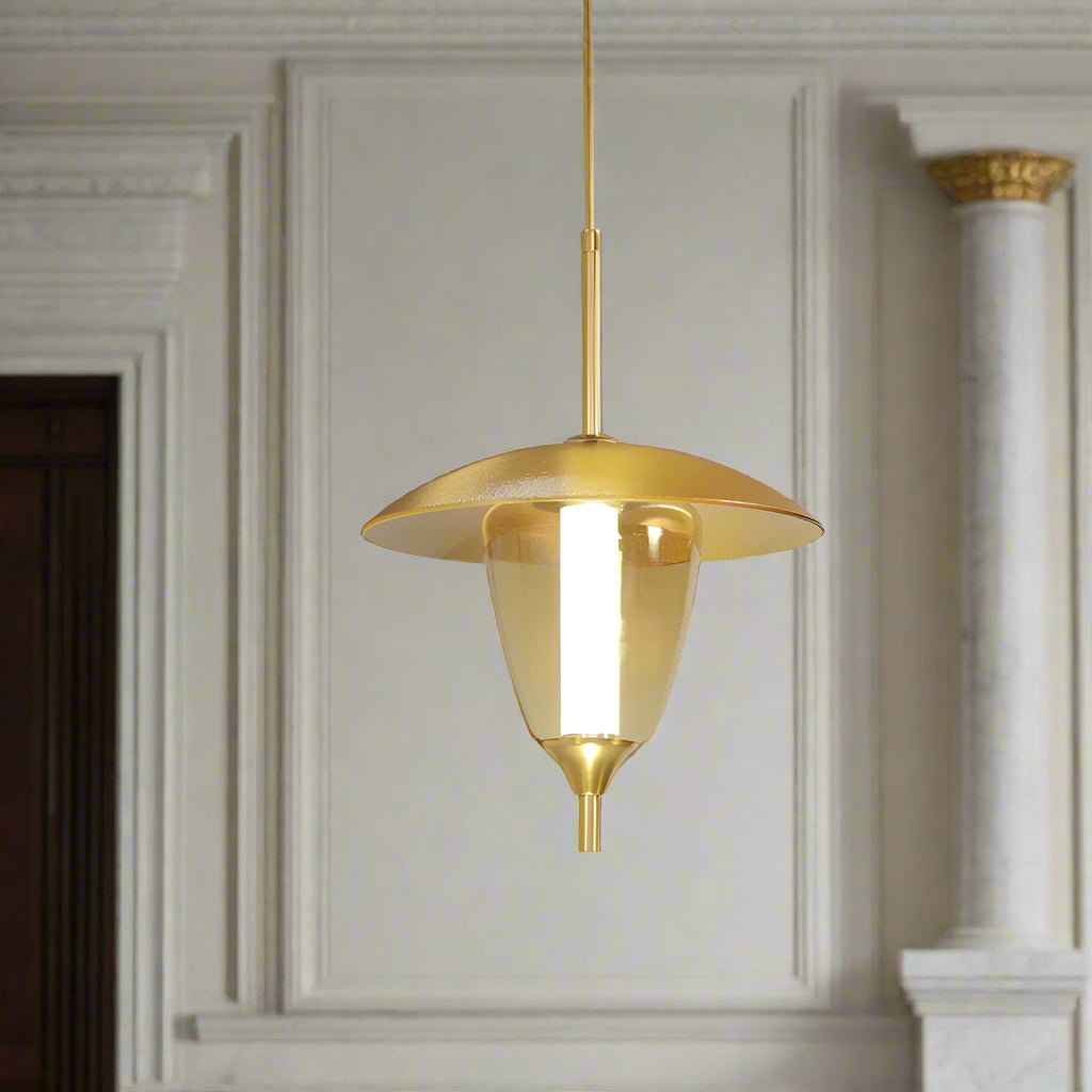 Gold pendant light hanging in a room with framed pictures on the wall.