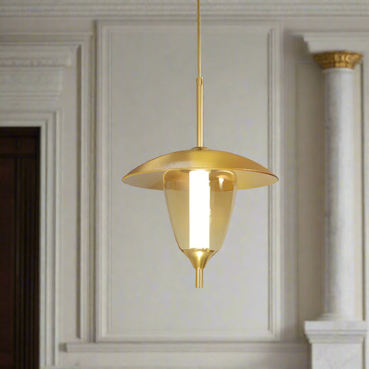 Gold pendant light hanging in a room with framed pictures on the wall.