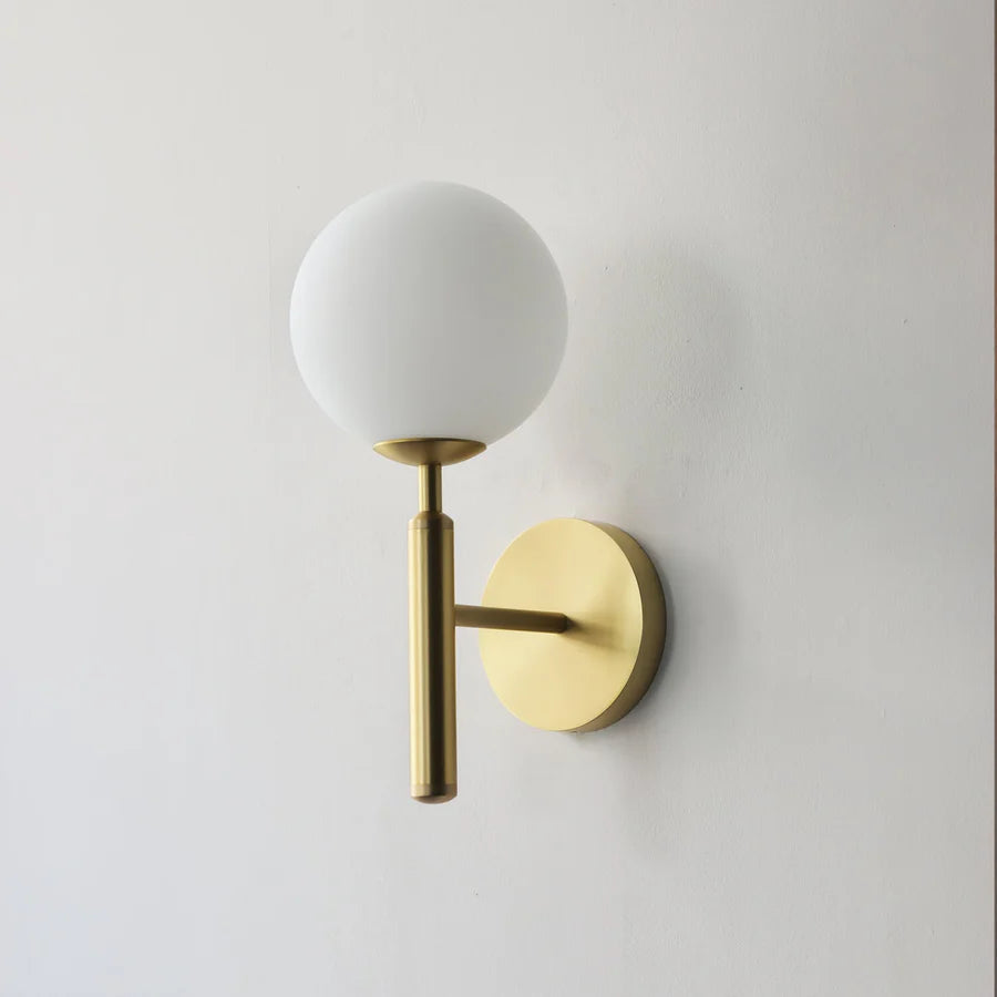 Wall-mounted GLOW CRYSTAL BALL LED WALL SCONCE LIGHT with gold finish and white globe on a plain wall.