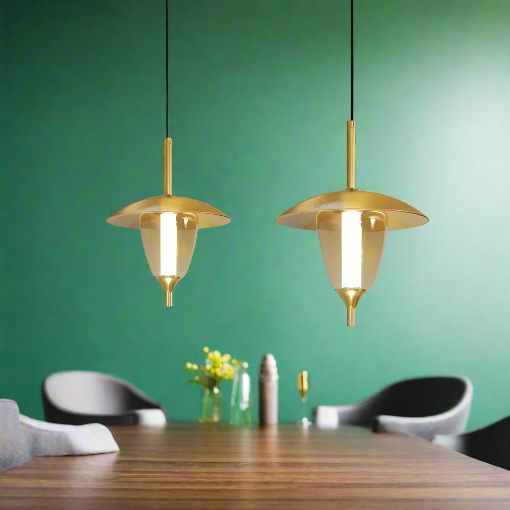 Two gold pendant lights hanging above a dining table in a modern room.