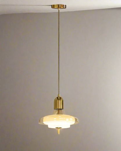 Pendant light with gold fixture and glass shade on a gray background