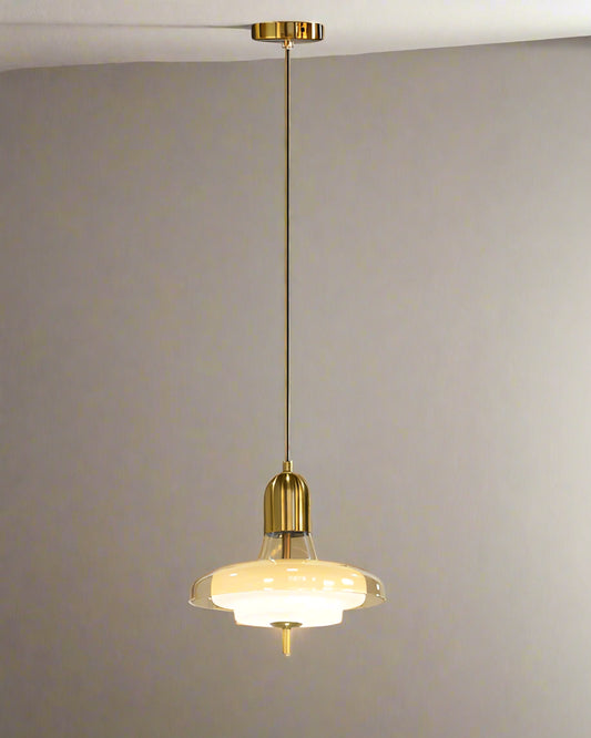 Pendant light with gold fixture and glass shade on a gray background